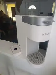 Single-serve coffee maker photographed in a water-damaged kitchen